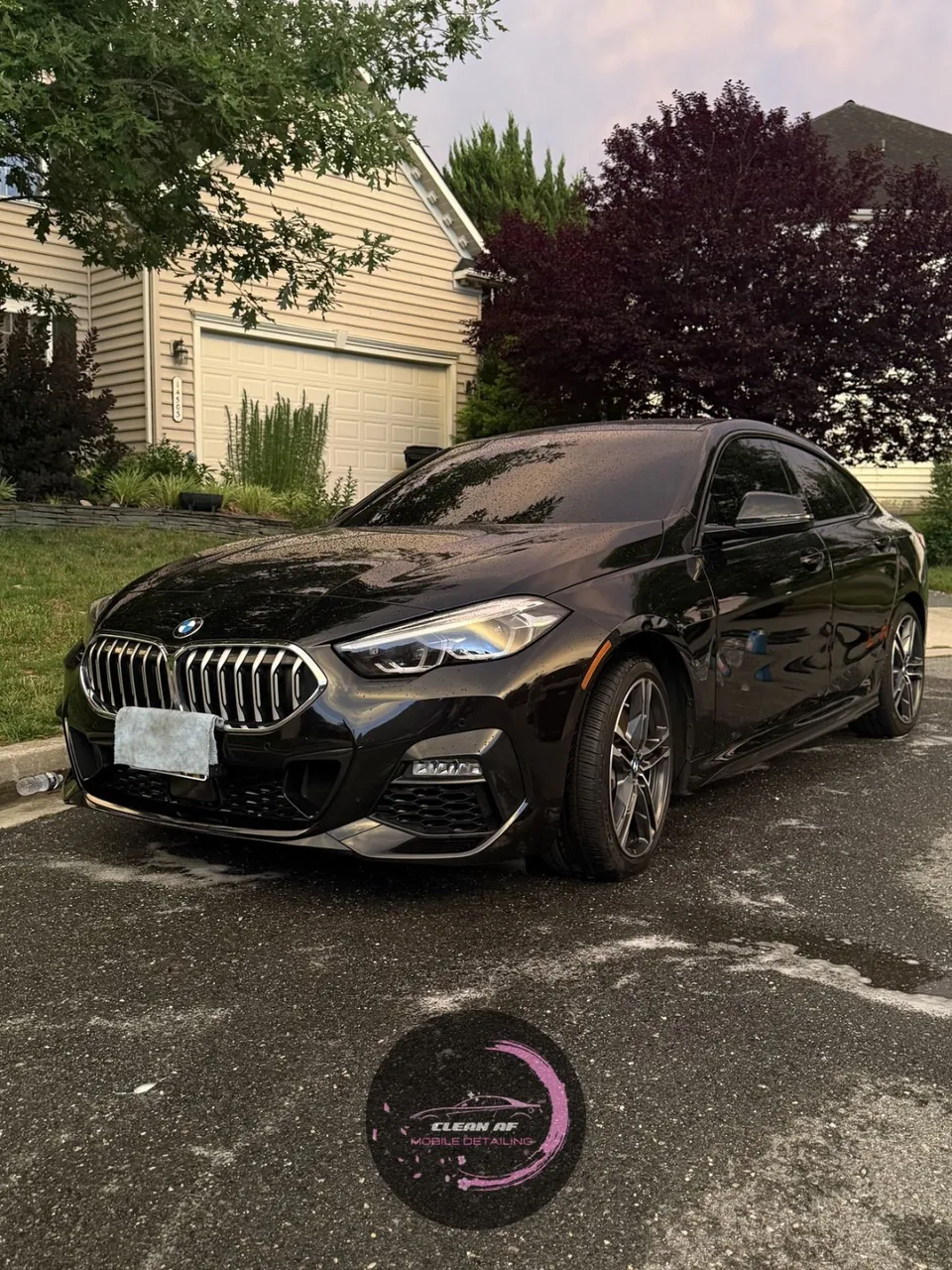 Black BMW sedan in a residential driveway after a Clean AF exterior detail