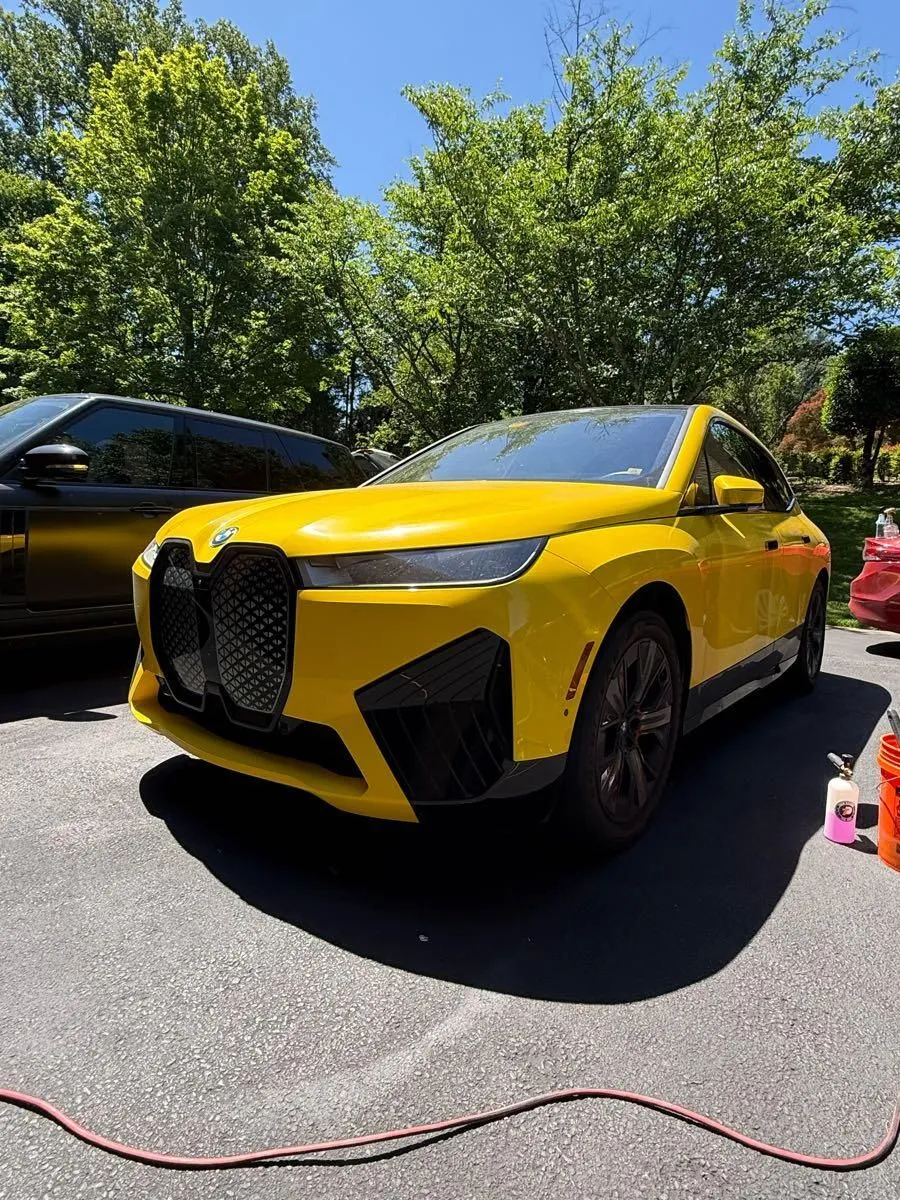Yellow BMW iX electric SUV on a driveway after a detail