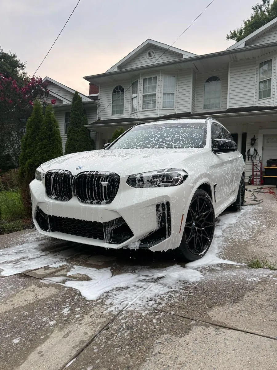Foam wash on a white BMW SUV parked in front of a house