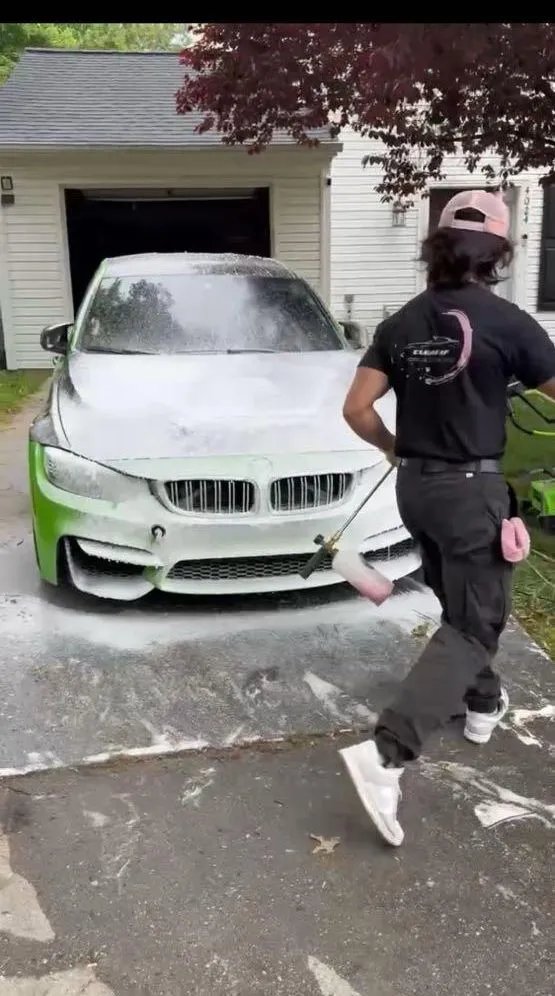 Clean AF detailer foaming a BMW coupe in front of a garage