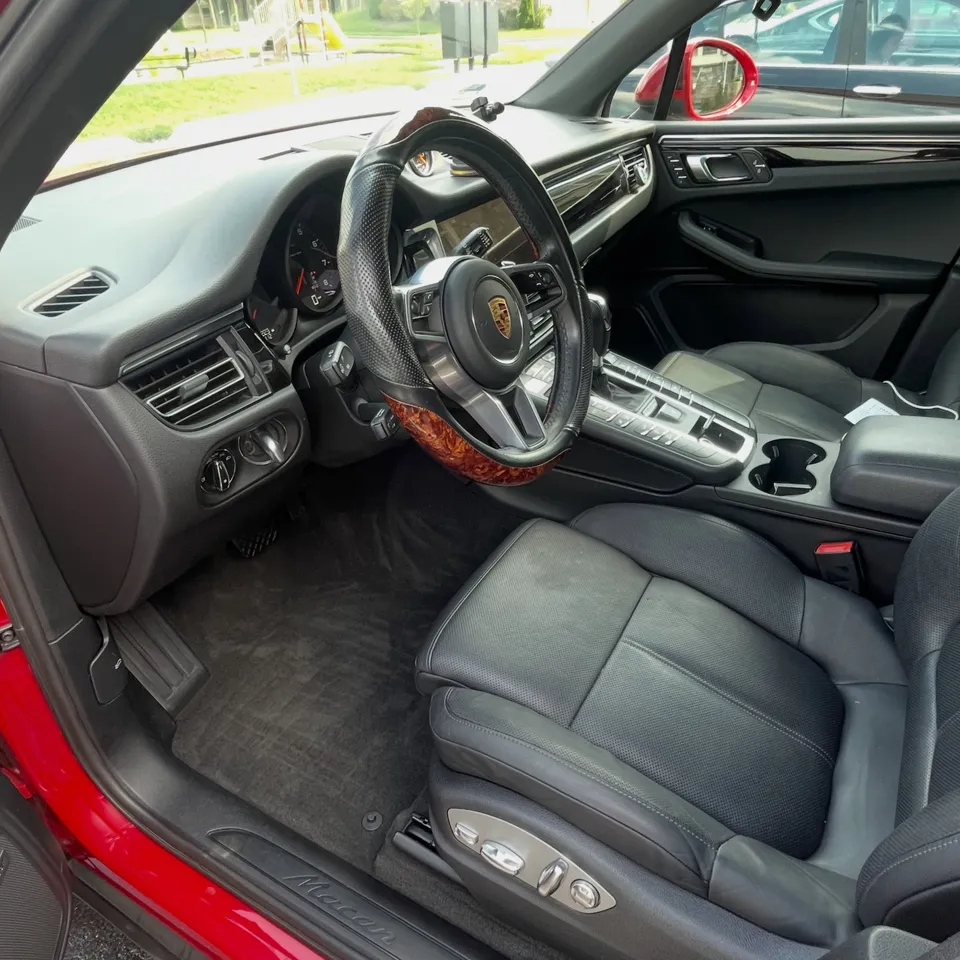 Porsche interior with black leather seats and clean carpets after an interior detail