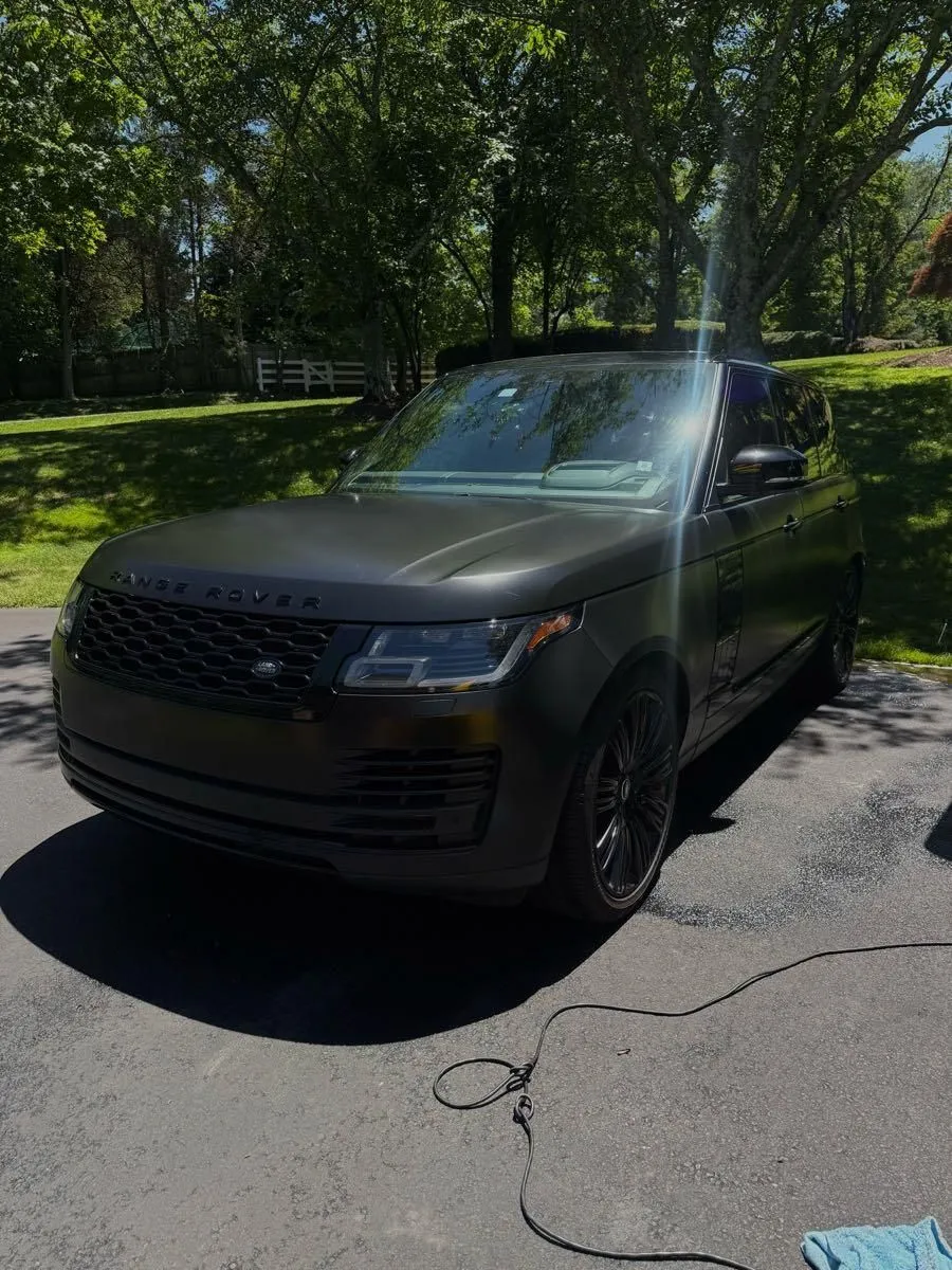 Black Range Rover on a driveway with the water hose still out